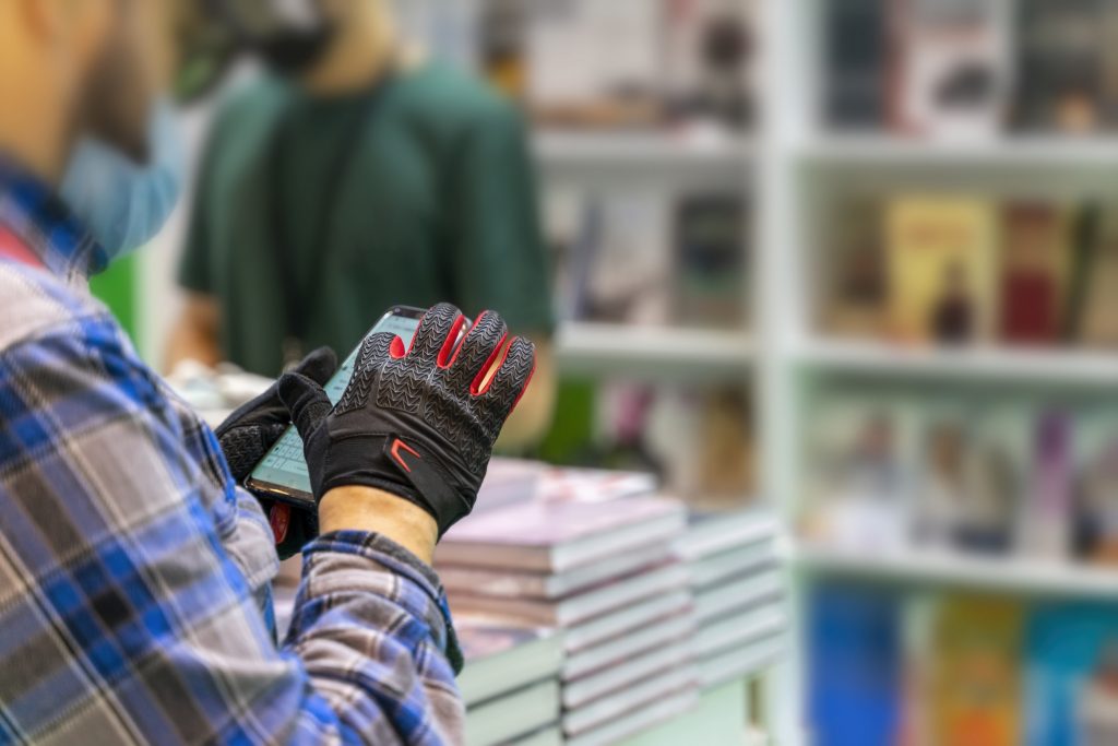 Retail employee using an edge device for inventory management. Edge computing in the retail industry bridges IT and operational technology, allowing in-store staff to manage devices and inventory with real-time updates.